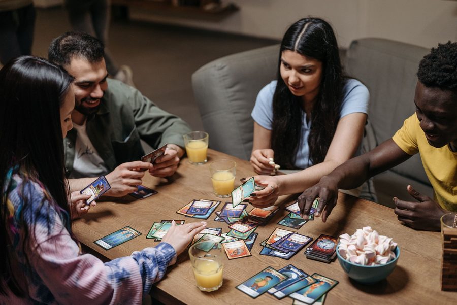 Four friends laughing over a card game at a table