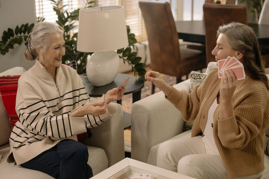 Two women laughing over their cards in a sitting room